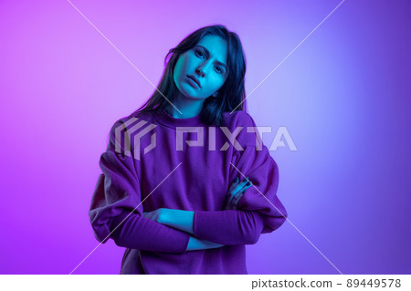 Studio shot of young attractive girl, student with long hair isolated over purple studio background in neon light. Concept of emotions, art, beauty 89449578