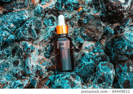 Cosmetic template. Glass bottle with pipette, with cosmetic serum or facial oil on blue stones, close-up. Top view. The concept of cosmetics and skin care 89449652