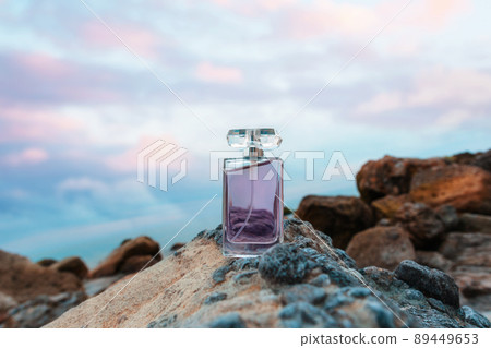 Transparent rectangular bottle with purple perfume on rock. Copy space. Concept of luxe perfumery and cosmetics Transparent rectangular bottle with purple perfume on rock. Copy space. Concept of luxe perfumery and cosmetics 89449653
