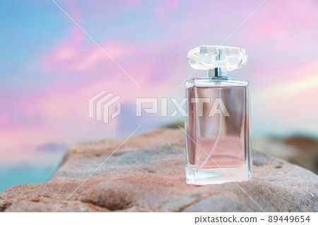 Beautiful glass bottle with purple perfume on white rock. Copy space. Concept of luxe perfumery and cosmetics Beautiful glass bottle with purple perfume on white rock. Copy space. Concept of luxe perfumery and cosmetics 89449654