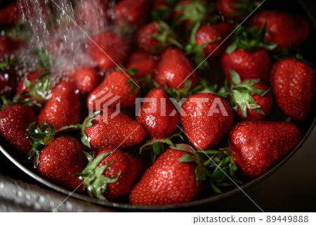 Juicy ripe red strawberries are washed in a steel bowl full of water. 89449888