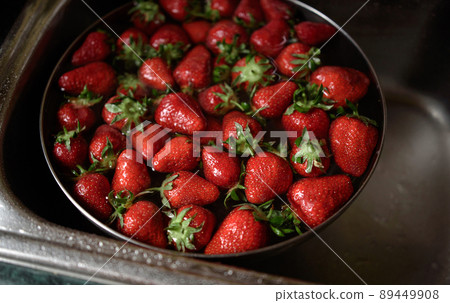 Juicy ripe red strawberries are washed in a steel bowl full of water. Juicy ripe red strawberries are washed in a steel bowl full of water. 89449908