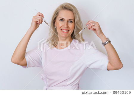 An adult woman beautician dermatologist holds brushes for creams and masks 89450109