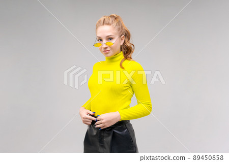 Portrait an attractive stunning cheerful slender girl, posing in bright yellow 89450858