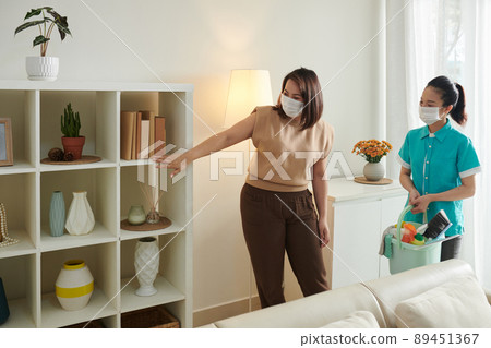 Woman Asking Cleaner to Dust Shelves 89451367