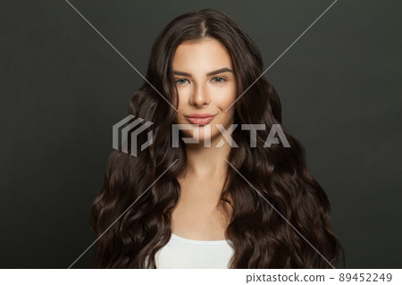 Cute woman with long curly beautiful hair smiling on black background Cute woman with long curly beautiful hair smiling on black background 89452249
