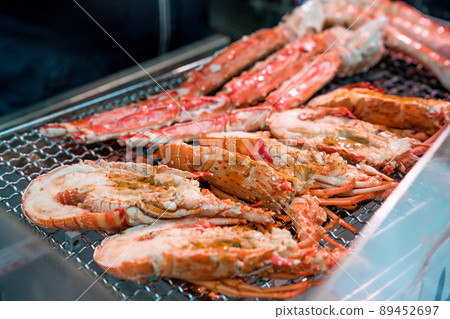Grilled shrimps and crab on the grill are fire and cooked in fish market, Japan Grilled shrimps and crab on the grill are fire and cooked in fish market, Japan 89452697