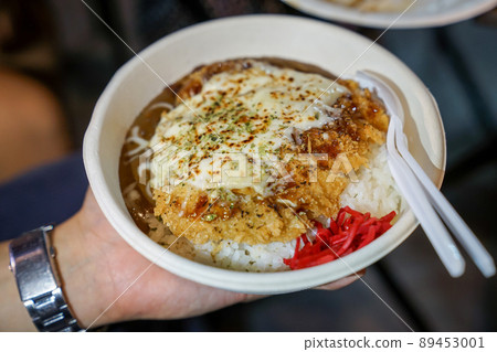Tonkatsu; traditional Japanese food, crispy fried pork with sauces on top and rice under it, in the paper dish. Food street of Bangkok, Thailand. 89453001