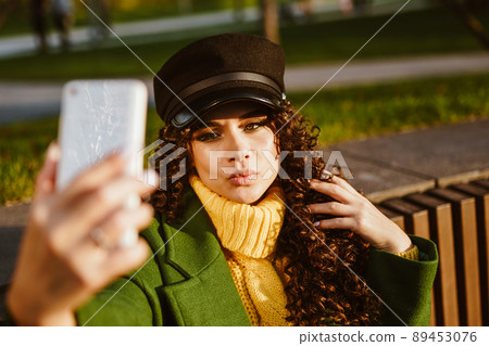 With a gloomy-looking girl taking a selfie in the park on the bench 89453076