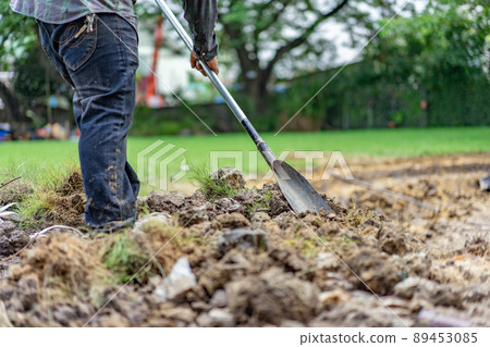 gardener digs the soil with his equipment for gardening and prepare land for plantation. gardener digs the soil with his equipment for gardening and prepare land for plantation. 89453085