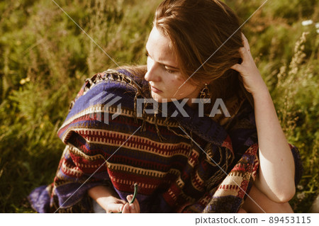 among the thickets of wormwood, a girl in an ethno cape straightens her red hair with her hands and looks thoughtfully down a close-up among the thickets of wormwood, a girl in an ethno cape straightens her red hair with her hands and looks thoughtfully down a close-up 89453115