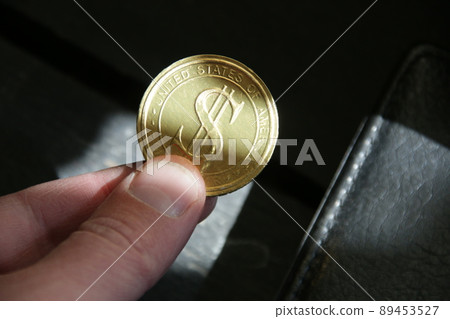 The hand holds a golden dollar coin. Successful business. The hand holds a golden dollar coin. Successful business. 89453527