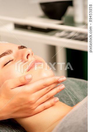 Facial massage. Hands of a masseur massaging neck of a young caucasian woman in a spa salon, the concept of health massage Facial massage. Hands of a masseur massaging neck of a young caucasian woman in a spa salon, the concept of health massage 89453858