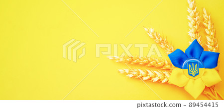 Blue yellow background. Ukrainian flower trident symbol with wheat grain ear isolated on yellow. Love Ukraine concept. 89454415