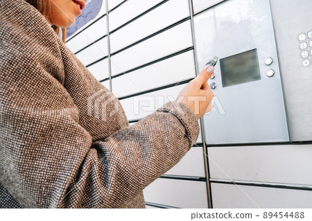 Delivery locker. Post automat terminal and hands with parcel courier box. Online purchase delivery service concept. 89454488