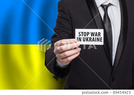 Stop war in Ukraine. Person holding banner on Ukrainian flag background 89454923