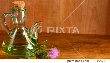 Flowers and oil of thistle on a wooden background. Wide photo. Flowers and oil of thistle on a wooden background. Wide photo. 89455218