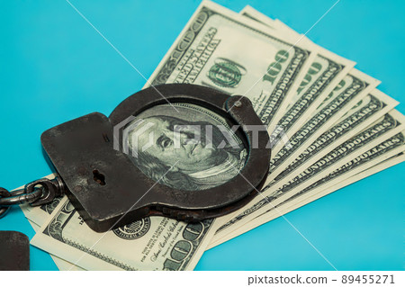 Handcuffs for money. Close-up of handcuffs on a hundred banknotes. Handcuffs on the background of Handcuffs for money. Close-up of handcuffs on a hundred banknotes. Handcuffs on the background of 89455271