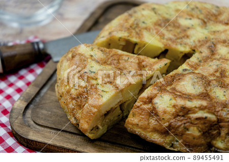 Close-up of a cut portion of a typical Spanish potato omelette in a rustic setting. Spanish Cuisine. Normal view. 89455491