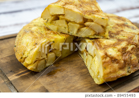 Close-up of a cut portion of a typical Spanish potato omelette in a rustic setting. Spanish Cuisine. Normal view. Close-up of a cut portion of a typical Spanish potato omelette in a rustic setting. Spanish Cuisine. Normal view. 89455493