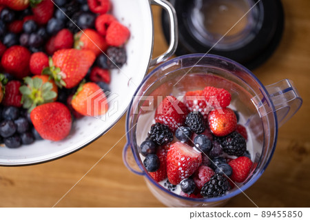 pouring milk into the blender for berry smoothie 89455850