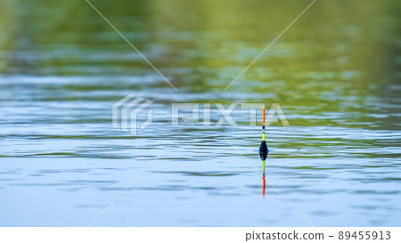 Yellow-orange fishing float on the surface of the water Yellow-orange fishing float on the surface of the water 89455913
