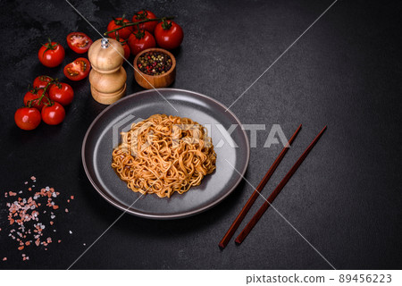 Buckwheat flour noodles with sauce, sesame, herbs and spices on a dark concrete background Buckwheat flour noodles with sauce, sesame, herbs and spices on a dark concrete background 89456223