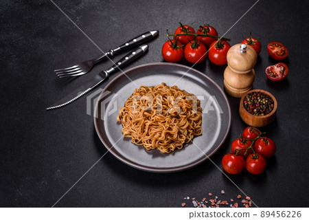 Buckwheat flour noodles with sauce, sesame, herbs and spices on a dark concrete background Buckwheat flour noodles with sauce, sesame, herbs and spices on a dark concrete background 89456226