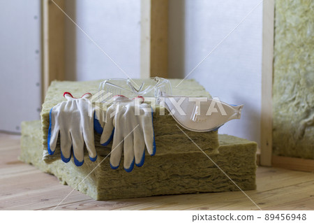 Rock wool and fiberglass insulation staff material for cold barrier. Tools for work with glass wool: protective goggles, glasses and mask. Warm home, economy, construction and renovation concept. 89456948