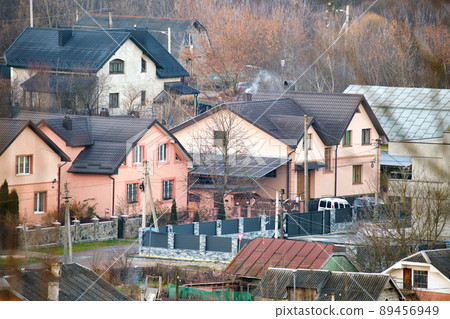 Residential houses with roof tops covered with metallic and ceramic shingles in rural suburban area 89456949