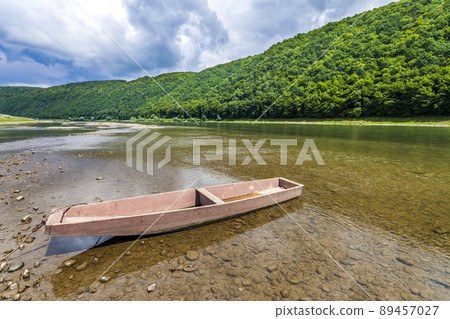 Old boat on clear water of the river with forest covered hills behind. Old boat on clear water of the river with forest covered hills behind. 89457027