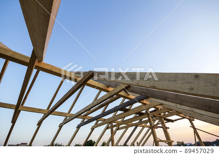 New wooden house under construction. Close-up of attic roof frame against clear sky from inside. Ecological dream home of natural materials. Building, construction and renovation concept. New wooden house under construction. Close-up of attic roof frame against clear sky from inside. Ecological dream home of natural materials. Building, construction and renovation concept. 89457029