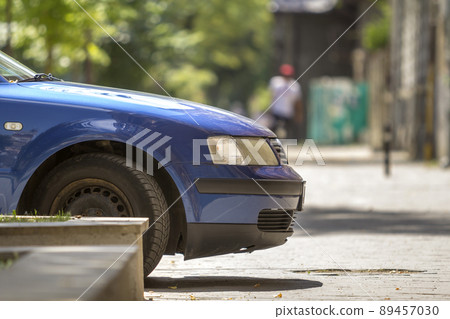 New shiny luxurious blue car parked on green trees bokeh background. New shiny luxurious blue car parked on green trees bokeh background. 89457030