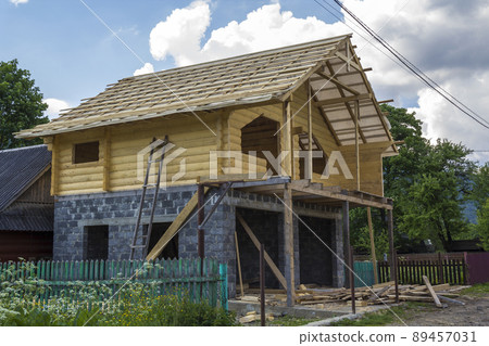 New cottage of natural lumber materials under construction. Wooden walls and roof on high brick stone garage. Property, investment, professional building and reconstruction concept. New cottage of natural lumber materials under construction. Wooden walls and roof on high brick stone garage. Property, investment, professional building and reconstruction concept. 89457031