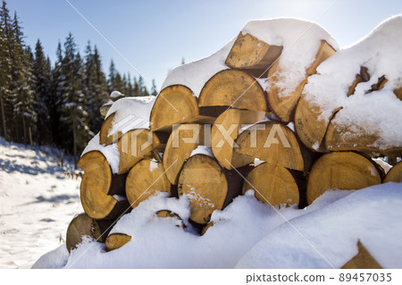 Neatly piled stack of chopped dry trunks wood covered with snow outdoors on bright cold winter sunny day, abstract background, Fire wood logs prepared for winter, ready for burning. Neatly piled stack of chopped dry trunks wood covered with snow outdoors on bright cold winter sunny day, abstract background, Fire wood logs prepared for winter, ready for burning. 89457035