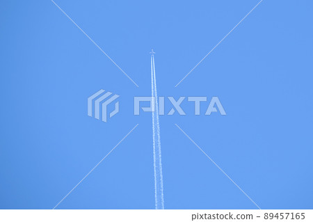 Distant passenger jet plane flying on high altitude on clear blue sky leaving white smoke trace of contrail behind. Air transportation concept. 89457165