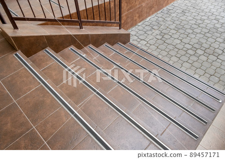 Concrete entrance stairs covered with ceramic tiles with metal railings outdoors. Concrete entrance stairs covered with ceramic tiles with metal railings outdoors. 89457171