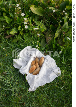 Composition of white flour buns in basket with white white cloth napkin on the green grass. High quality photo Composition of white flour buns in basket with white white cloth napkin on the green grass. High quality photo 89457292