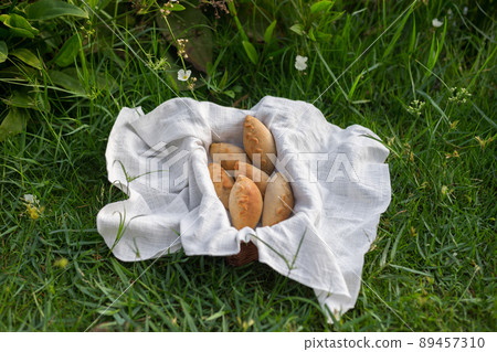 Composition of white flour buns in basket with white white cloth napkin on the green grass. High quality photo 89457310