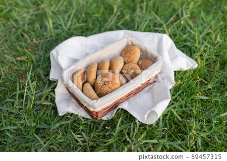 Composition of white flour buns in basket with white white cloth napkin on the green grass. High quality photo 89457315