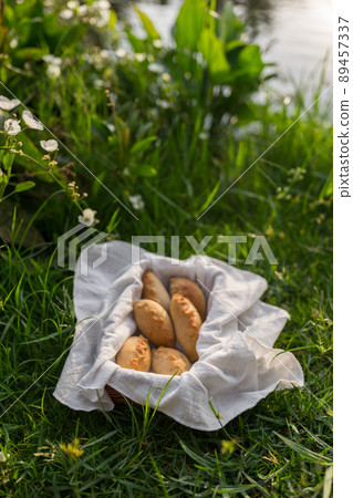Composition of white flour buns in basket with white white cloth napkin on the green grass. High quality photo 89457337
