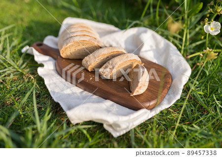 Composition of homemade white flour bread on wood board with white cloth napkin on the green grass . High quality photo Composition of homemade white flour bread on wood board with white cloth napkin on the green grass . High quality photo 89457338