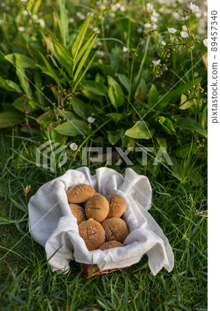 Composition of white flour buns in basket with white white cloth napkin on the green grass. High quality photo 89457340