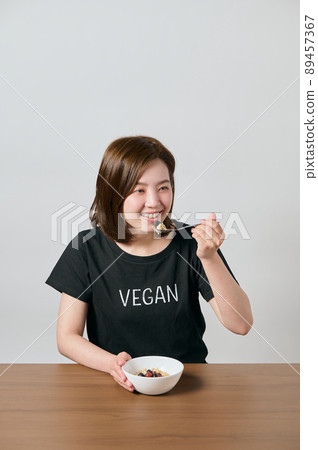 Young vegan woman eating oatmeal Young vegan woman eating oatmeal 89457367