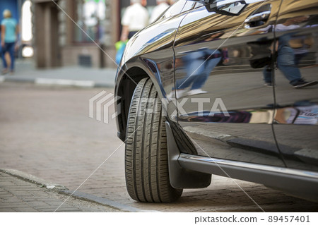 Close up detail part of car wheel with new black rubber tire protector on light blurred copy space background. Transportation, safety, reliability, modern design concept. Close up detail part of car wheel with new black rubber tire protector on light blurred copy space background. Transportation, safety, reliability, modern design concept. 89457401