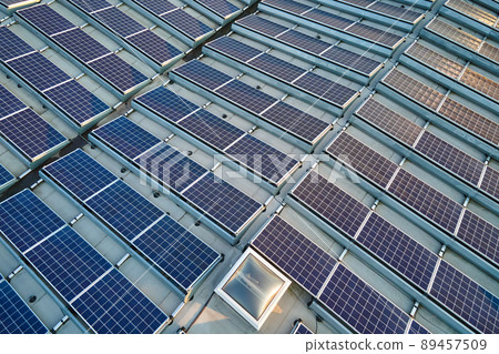 Aerial view of solar power plant with blue photovoltaic panels mounted on industrial building roof for producing green ecological electricity. Production of sustainable energy concept 89457509