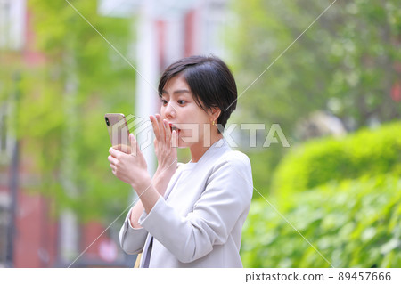 A woman who is surprised to see a smartphone and holds her mouth in her hand 1 89457666
