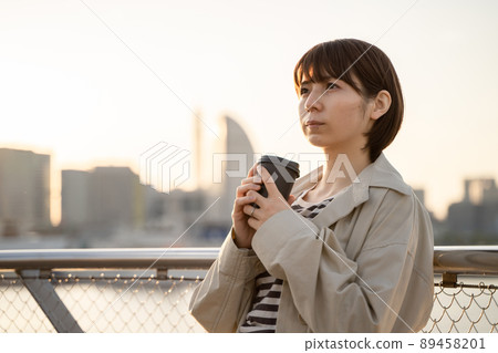 A pensive woman drinking coffee outdoors 89458201
