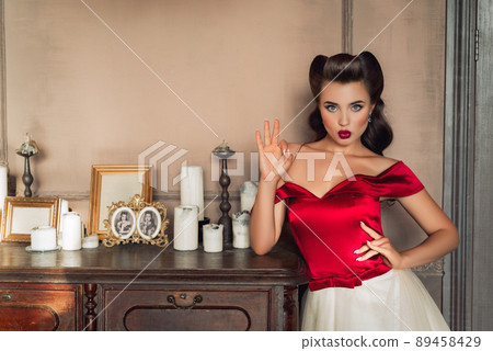Pretty coquettish pin-up girl in retro interior. OK gesture 89458429
