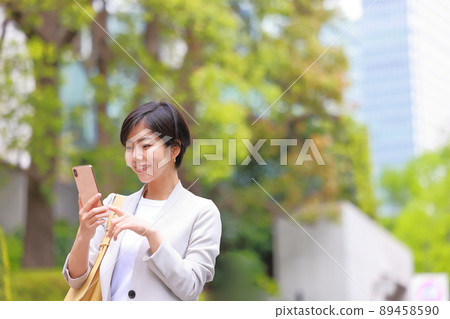 Fresh green office district_Business woman operating a smartphone 1 89458590